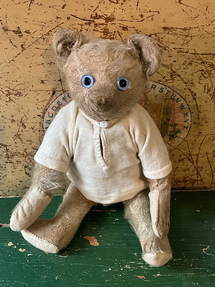 11.5” Antique white mohair bear. This old boy has had all pads replaced some time ago and only a few rust claw stitches remain. Being white at one time, he has sustained  some soiling that would be a natural result of being someone’s beloved companion. His antique blue eyes are most likely not original, but have been with him for the 25 or so years that he has been in my collection. He comes wearing an antique cotton top with mother of pearl button at the neck. A harder to locate antique white bear at a nice price. $ 265.00 postage paid