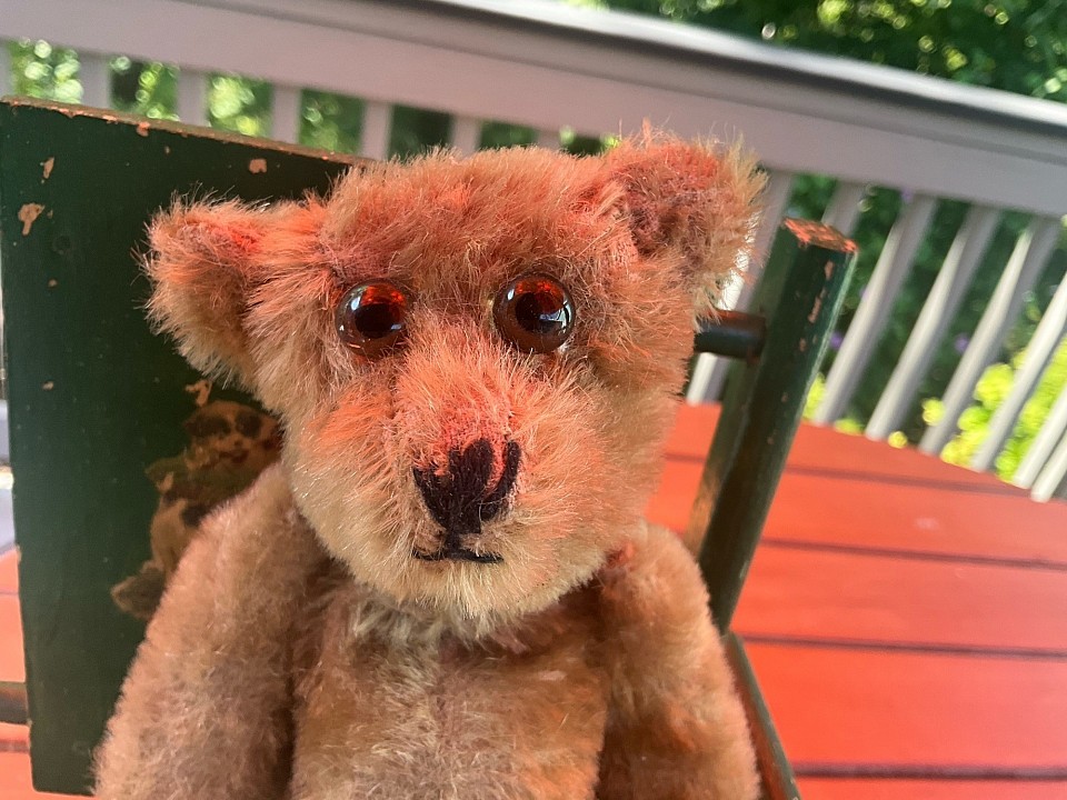 8.5” bear with humpback and bulbous glass amber eyes. Wearing antique pink cotton romper.